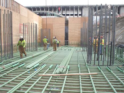 This photo shows the lower layer of pier footing reinforcement for the I-35W bridge. The reinforcement was placed such that the drilled shaft reinforcement could extend through into the core of the footing. The depth of the footing can be seen by the form work height (14ft (4.8 m)).