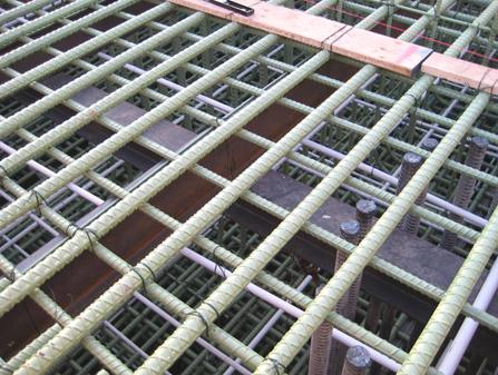 This photo shows the upper layer of pier footing reinforcement for the I-35W bridge. There are steel beams attached to the drilled shaft reinforcement. Cooling tubes can also be seen running through the footing along with the footing reinforcement.