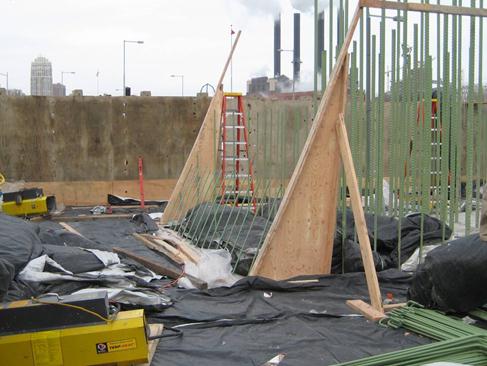 This photo shows reinforcement for the first column pour for I-35W bridge columns. The columns cast onto the footing were constructed in three steps. The lower-most phase is shown being formed. The black plastic at the base of the column covers the footing, providing a thermal insulation to avoid unwanted differential temperature induced stresses. The first level of each column totals 200 yd3 (153 m3) of concrete.