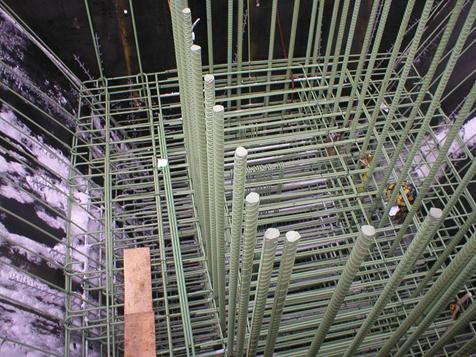 This photo shows longitudinal and horizontal column reinforcement. The reinforcement extending from the midsection of the column is shown from the top view with the uppermost formwork in place (black). Multiple levels of transverse steel were installed in both directions. Snow lines the inside of the upper column formwork.