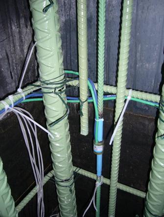 The photo shows the corner of one of the columns. At the bottom of the upper-most portion of the column where the column is smallest (midheight), dual mode strain gauges were installed at each of the four corners. The green and blue wires represent the resistance and vibrating wire type gauges, respectively.