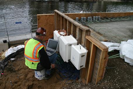 The photo shows the temporary data acquisition system (DAS) being reconnected aside the southbound pier 2 footing. The temporary DAS was removed from the fence line and reconnected, reconfigured, and reattached in a second temporary location while the vault for a permanent DAS was constructed.