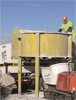 Figure 3. Photo. Portable concrete pan mixer preparing UHPC for placement during the construction of the field-cast connections. This photograph shows a worker facilitating the mixing of ultra-high performance concrete (UHPC) in a portable pan mixer during a field-casting of UHPC connections.