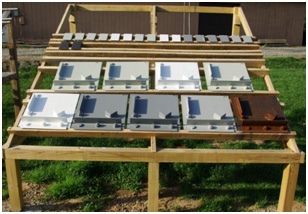 This photo shows a wooden rack in the backyard of Turner-Fairbank Highway Research Center (TFHRC) in McLean, VA. The rack is a natural weathering only (NW) rack. Type I and type II test panels were deployed on wooden runner panels installed on the frames of the wooden rack, which is inclined at 30 degrees facing south. The horizontal runners have non-metallic hinges to support the test panels as they are deployed.