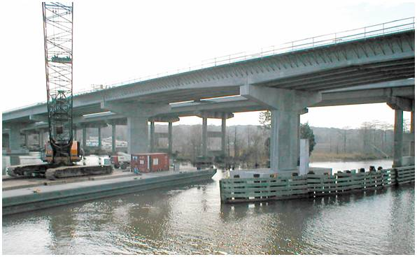 Figure 18. Photo. Precast spliced girder bridge. This photo shows a nearly completed precast spliced girder bridge over a body of water
