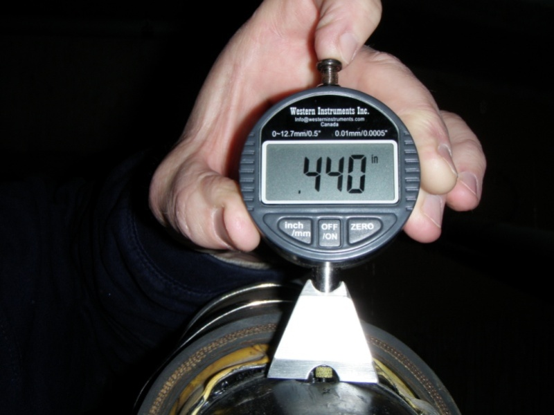 Figure 53. Photo. Dial gauge used to determine the depth of a grout air void. This photo shows a hand holding a dial gauge used to measure duct thickness. It is placed above a location on a tendon where a small section of duct has been removed.