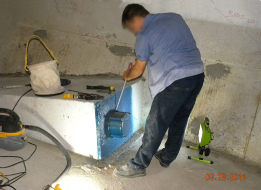 Figure 62. Photo. Removing a permanent grout cap. This photo shows a worker using a screwdriver and hammer to pry off the end cap on an internal tendon.