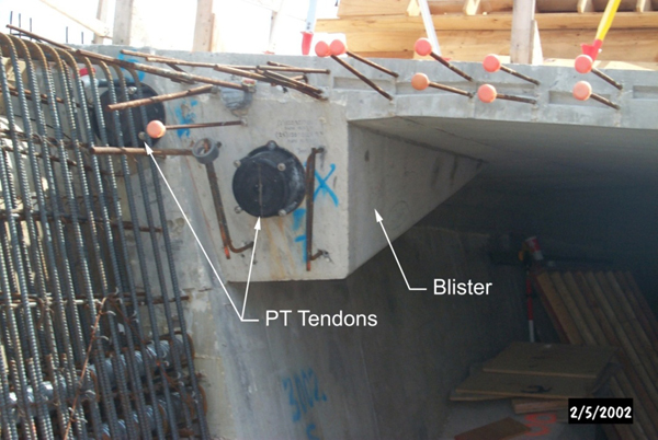 Figure 9. Photo. Blister at the top flange. This photo shows the end of a cast-in-place box girder on a bridge under construction. There is a blister at the top flange with two tendons