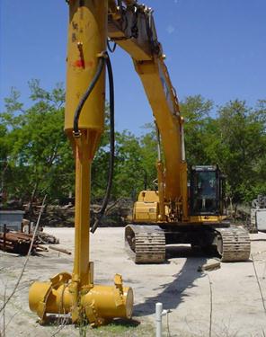 This photo shows an excavator arm with a horizontally oriented mixing barrel at the end.