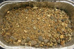 The image shows the “as received” Illinois gravel aggregate used in mix designs. The “as received” aggregates were assessed and crushed if necessary to fit ASTM C1260 grading requirements before being used to create concrete prism samples under the ASTM C1293 testing procedure.