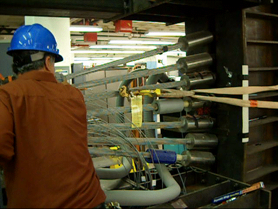 This photo shows a mechanism to apply load to prenotched wires. The mechanism is designed to pull the notched wires to failure mounted on the cable and during the pulling phase. An engineer is observing the pulling clamp to ensure that no slippage occurs along the wire. 