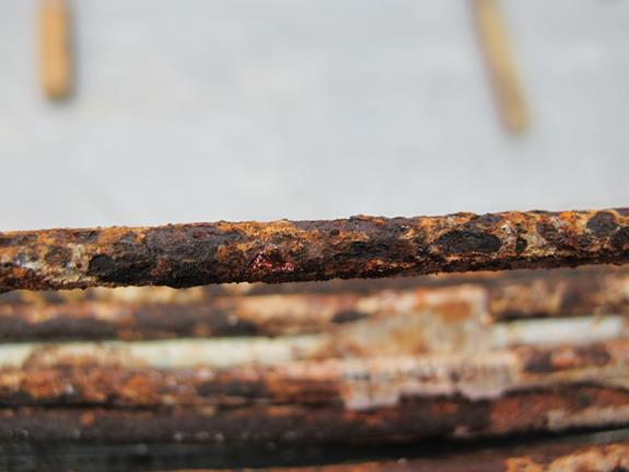 This photo shows a close-up view of the corroded wire from figure 132. An individual wire with severe ferrous corrosion and corrosion product is visible. 