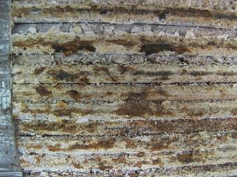 This photo shows wires under the cable band showing sign of stage 3 corrosion. A close-up of an area of approximately 3 by 3 inches (76.2 by 76.2 mm) highlights white zinc and rust colored ferrous corrosion product. 