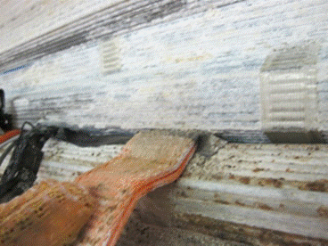 This photo shows an orange nylon strap embedded within the cable near the sensor locations. The straps are approximately 1.5 inches (38.1 mm) wide and used to protect the sensors from the compaction forces applied to the cable. A small bit of stage 3 corrosion can be seen on one of the strands in the image. 