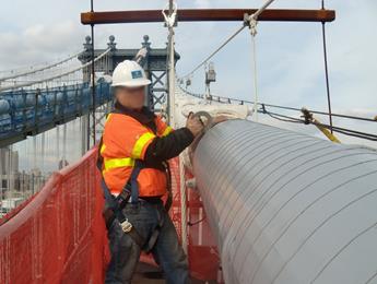 A worker is seen rewrapping the instrumented north cable section from the suspended platform. The cable was rewrapped with a neoprene wrapping system. 