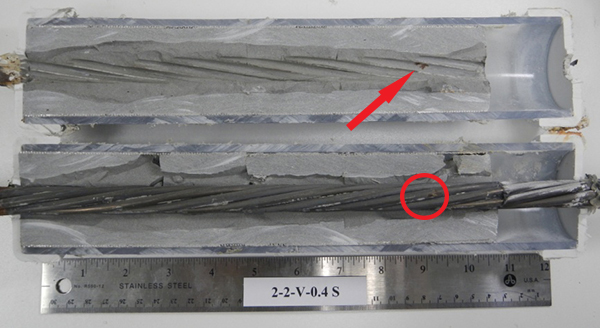 Figure 194. Photo. Stressed single-strand specimen with void and 0.4 percent chloride. This photo shows the as-extracted condition of a 0.4 percent chloride stressed single-strand specimen with void. A rust spot found on the strand is indicated by a red circle, and a matching rust stain on the grout side is indicated by a red arrow.