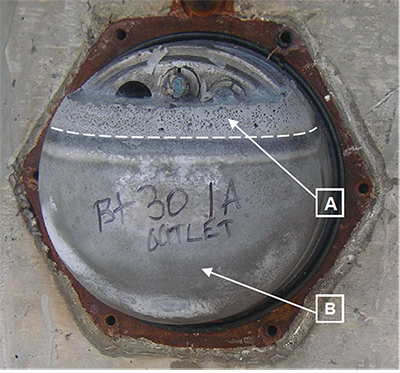 Figure 2. Photo. Chloride-contaminated grout in the saddle caps for Carbon Plant Road bridge. This photo shows a chloride-contaminated grout in the saddle caps for Carbon Plant Road bridge. There are two labels with arrows pointing at different locations. Label A indicates normally hardened grout, and label B indicates defective grout that contained numerous air voids. 