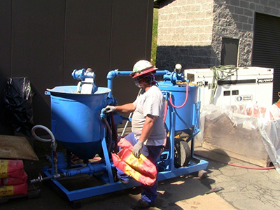 Figure 32. Photo. Grout mixing. This photo shows a worker using an industrial grade mixer to mix grout.