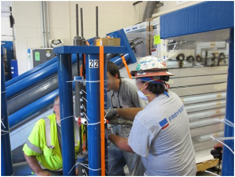 Figure 33. Photo. Grout pumping into a single-strand specimen. This photo shows workers using a machine to pump grout for task 2.2 specimens.