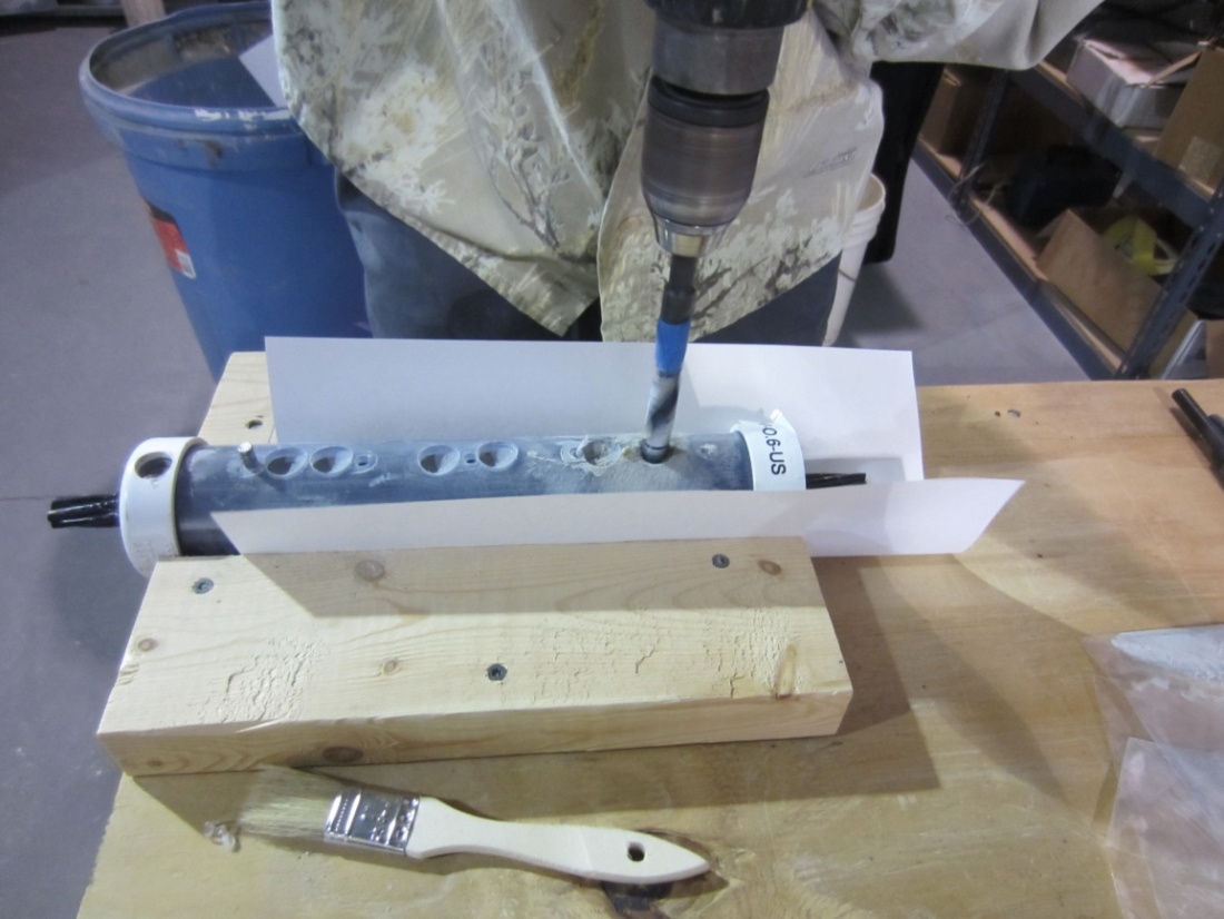 Figure 59. Photo. Grout powder sampling from a single-strand specimen. This photo shows a person using a masonry drill on a single-strand specimen and the grout powder sampling from it.