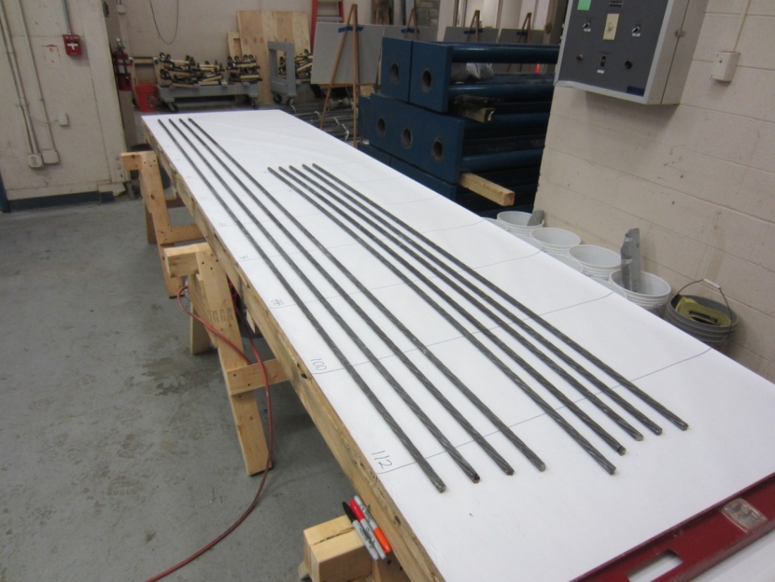 Figure 74. Photo. Inspecting PT strands removed from a multi-strand specimen on an autopsy table. This photo shows the extracted post-tensioned (PT) strands placed on a specially constructed autopsy table for detailed inspection.