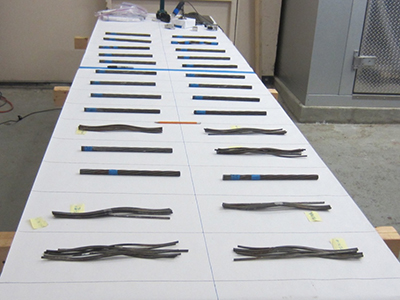 Figure 75. Photo. Several 12-inch-long cut-out segments exhibiting various corrosion conditions. This photo shows numerous 12-inch segments placed on the autopsy table for detailed inspection. They exhibit various corrosion conditions.