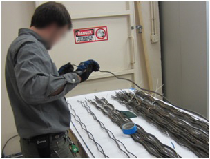 Figure 76. Photo. Cleaning and visual inspection of 7-ft-long unstressed strands. This photo shows a person cleaning and visually inspecting 7-ft-long unstressed strands retrieved from the multi-strand specimens. 
