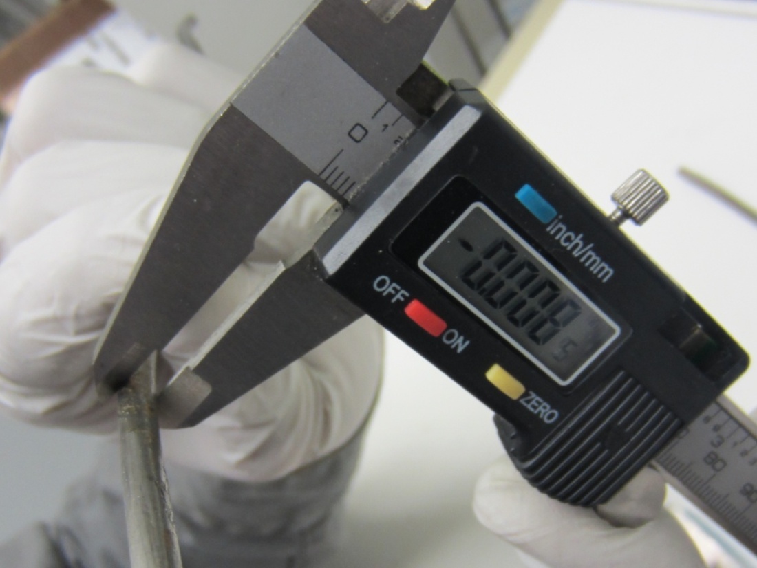 Figure 78. Photo. Section loss measurement in a severely corroded area. This photo shows a wire with excessive section loss being measured using a digital micrometer. 