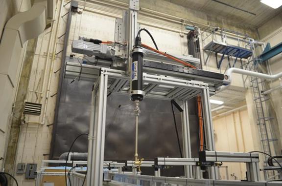 This photo shows the acoustic Doppler velocimeter probe extending downward from the robot positioned to be lowered into the flow field in the flume. 