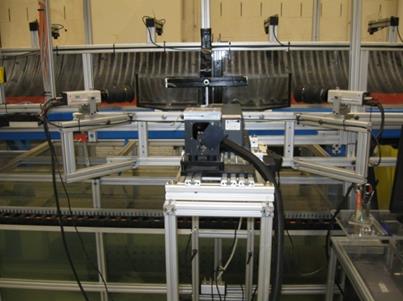 This photo shows the stereoscopic particle image velocimeter mounted beside the flume oriented to scan the flow field. The laser is situated in the center with a camera mounted on the left and right sides of the laser. 