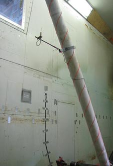 This photo shows a Turbulent Flow Instrumentation (TFI) Cobra Probe attached to the cable model to measure the turbulence level behind the grid of ladders. The cable model is used to support the probe at several heights above the floor. The probe is clamp-mounted 430 mm in front of the cable model.