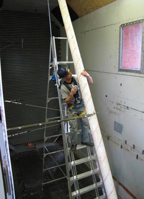 The photo shows the cable model physically inspected by a researcher standing on a ladder. The attachment of helical fillet is being checked.