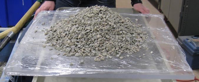 The photo shows a conical pile of aggregate on a plastic board to measure the angle of repose.