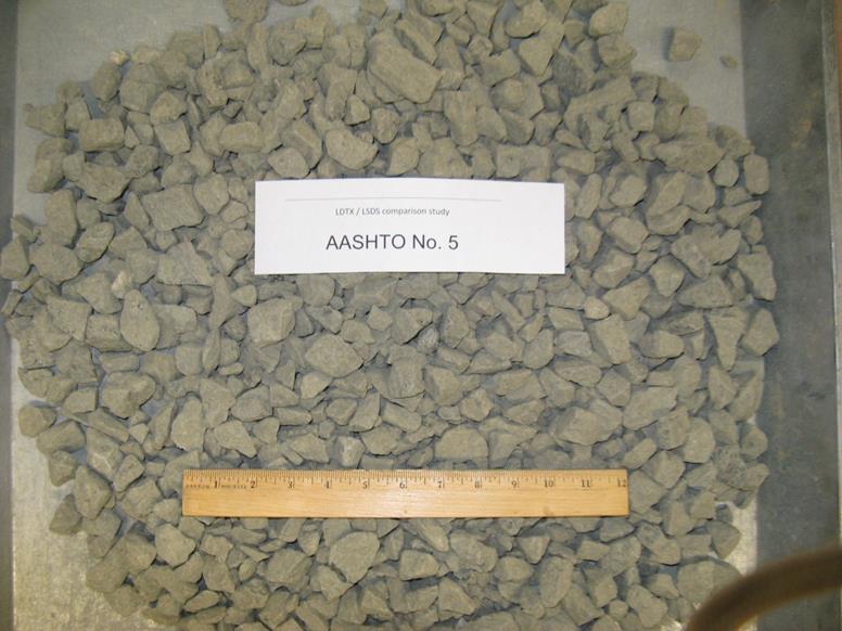 This photo shows the American Association of State and Highway Transportation Officials M43 gradation-based designated No. 5 aggregates with a diabase rock source supplied from a quarry in Ashburn, VA. The maximum values of dmax and d50, in inches are 1.5 and 0.847, respectively. They are classified as a poorly graded gravel based on the Unified Soil Classification System. The minimum and maximum unit weights, in pounds per cubic ft, are 94.9 and 109.6, respectively.