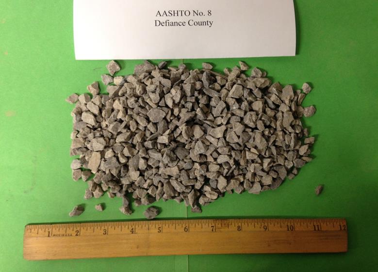 This photo shows the American Association of State and Highway Transportation Officials M43 gradation-based designated No. 8 aggregates with a limestone rock source from the Devonian period, supplied from a quarry in Defiance County, OH. The maximum values of dmax and d50, in inches, are 0.50 and 0.250, respectively. They are classified as a poorly graded gravel based on the Unified Soil Classification System. The minimum and maximum unit weights, in pounds per cubic ft, are 85.7 and 101.3, respectively.