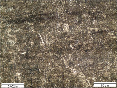 Figure 28. Photo. Micrograph near thread root etched with Marshall’s reagent at 500x magnification. This photo shows a micrograph that was taken near the thread roots of the threaded rod at a magnification of 500x and viewed under bright field illumination. The sample was etched with Marshall’s reagent. A scale bar with a length of 0.002 inches is shown in the lower left corner of the photo, and a scale bar with a length of 50 micrometers is shown in the lower right corner. The microstructure is mostly brown and appears as a needle-like martensite structure throughout most of the photo.