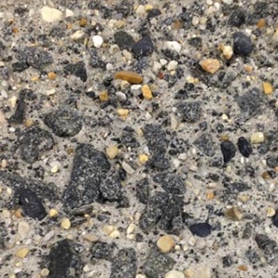 The photo shows the type of concrete surface obtained with exposed aggregate surface preparation methods, characterized by having a large degree of roughness.
