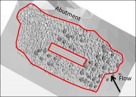 Figure 39. Graphic. Extent of riprap in the updated CFD model with movable rocks. This graphic shows the outline of pier 3 and the revised riprap extent. Movable rocks are shown in the graphic in a darker shade than the stationary rocks. Most of the movable rocks are placed upstream of the pier with a few on each side of the pier and a couple downstream of the pier.