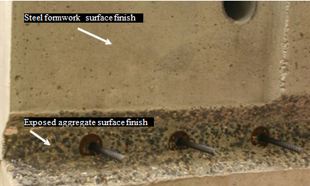 This photo shows the difference between the two finishes on ultra-high performance concrete (UHPC) connections. The finish of the beam as it is removed from the framework (i.e., steel framework surface finish) is visible in the top half of the photo and appears smooth to the touch. The surface of the connection in the bottom half of the photo (i.e., exposed aggregate (EA) surface finish) has the aggregate of the concrete exposed. It is much rougher, with the coarse EA of the concrete protruding from the surface.