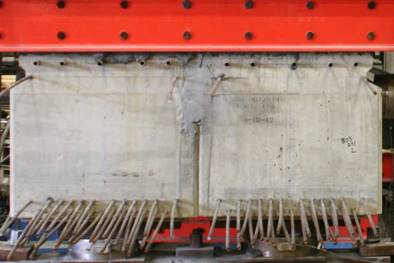 This photo shows an end view of two beams with partial-depth connections joined using conventional grout. The connection has already been poured, and the beams are resting on their end supports. The bulbous ultra-high performance concrete connection is visible on the outside of each beam.