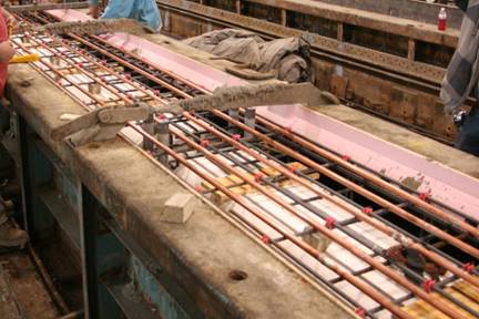 This photo shows copper tubing running in the top flange of a box beam prior to casting the top of the beam. Five lines of copper tubing can be seen resting on top of the top mat of reinforcement.
