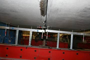 This photo shows the arrangement of the five linear variable differential transformers (LVDTs) located at the mid-span. Four are aligned vertically at each edge of each of the two beams. The fifth LVDT is aligned horizontally and spans across the gap between the two beams to measure separation.