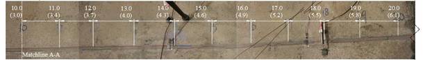 This figure shows the top of the two girders and the connection from the 10- to 20-ft (3.05- to 6.10-m) mark. Various marker lines are present on the connection grout and the interface between the beams and the connection. Red marker is visible throughout the entire connection, which indicates the extent of the mechanical cracking.