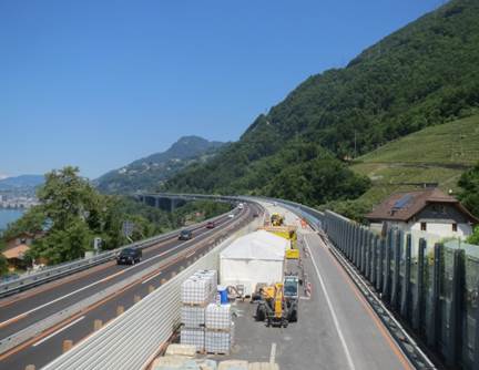 Figure 12. This figure shows a photo of the Chillan Viaduct UHPC overlay project during the second construction phase. The photo shows two roadway surfaces: the lefthand roadway depicts what the roadway looks like after the overlay has been installed along with the ride surface. Vehicles are shown driving on this completed portion; the righthand roadway shows construction operations during UHPC overlay installation.