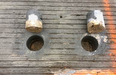 Figure 28. This photo shows two test samples after bond testing. Both samples exhibit Mode 1 failure, which is failure in the substrate concrete. The samples are shown next to their respective core locations.
