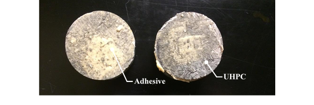 Figure 30. This figure shows two representative bond pull-off discs from G1 and G2 locations after testing. These sample exhibited Mode 4 failure, which is failure of the adhesive used to join the test disc with the UHPC overlay. The two test discs are shown side by side. The lefthand test disc is used to illustrate the adhesive remaining on the disc after testing, and the righthand disc is used to illustrate UHPC bonded to the disc.