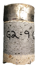 Figure 31-A. Photo. Front of G2-9 specimen after testing. This photo shows the front of the specimen where the steel test disc, UHPC overlay, and the substrate concrete can be observed. Mode 4 failure is evident by a thin crack between the test disc and the UHPC overlay material.