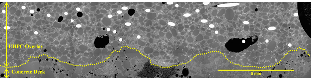 Figure 33. This figure shows an electron microscope image that depicts the interface between the UHPC overlay and the existing deck concrete. The image is shown to have a scale bar measuring 5 mm. The image shows a sound interface with close physical contact between hydrated phase of UHPC and the existing concrete deck substrate. Further, the existing deck scarification can be observed by the “peaks” and “valleys” denoted by a dotted line.