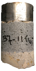 Figure 41-A. Photo. Front of B7-11 specimen after testing. This photo shows the front of the specimen. The steel test disc, UHPC overlay, and the substrate concrete can be observed. This specimen exhibits Mode 1 failure, which is failure within the substrate concrete. In this, substrate failure was due to a pre-existing delamination within the deck concrete.