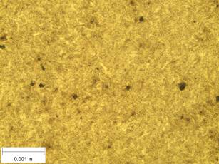 A scale bar is provided in the picture showing a dimension of 0.001 inch, and therefore the field of view is approximately 0.005 inch wide and 0.0038 inch tall. The image comprises two types of microstructures: light and dark. Both microstructures appear to be randomly distributed through the image and have grain sizes on the order of 0.0002 inch. The image also contains a random distribution of round inclusions, also around 0.0002 inch. The grain boundaries have started to become muted and less defined.